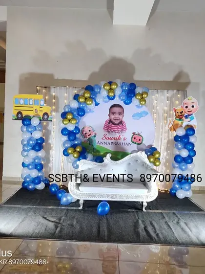 This Cocomelon themed setup was for an Annaprashan (first rice-eating ceremony). It features a small white sofa, character cutouts of JJ and his friends, and a blue and white balloon backdrop.