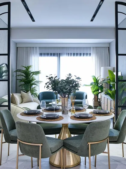 An elegant dining setup designed for memorable gatherings. This setting features a round marble-top table with a brass base, surrounded by custom-made green velvet dining chairs, all framed by dramatic arched glass partitions.