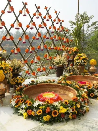 The central ritual area for the Haldi, featuring two large brass urlis filled with flowers, set before the beautiful bamboo backdrop.