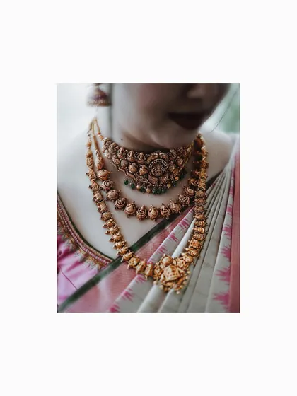 A close-up detail shot of the bride's stunning layered gold temple jewelry.