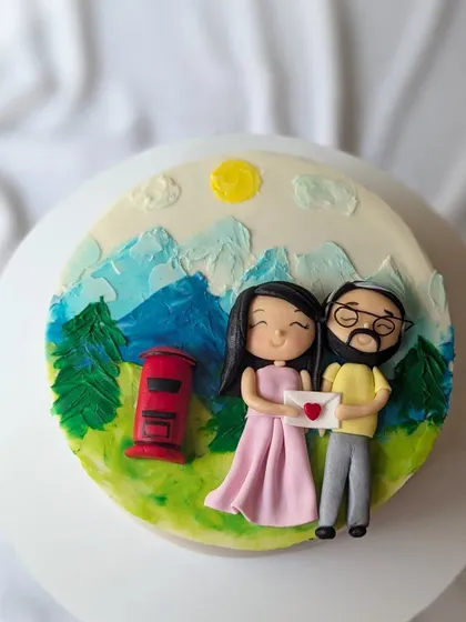 A love story set in the mountains. This cake features a hand-painted landscape and two cute figurines of the couple sharing a love letter.