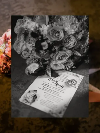 A detail shot in black and white, featuring the wedding rings on the invitation card next to the bridal bouquet. It's the little things that tell the big story.
