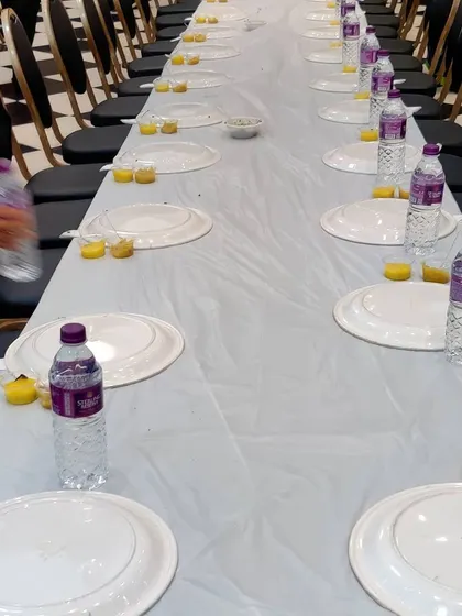 A simple and hygienic setup with plastic-covered tables and neatly arranged plates and water bottles. This is a practical option for many events.
