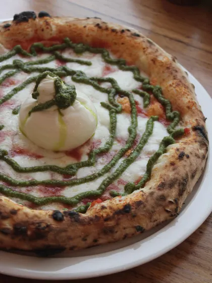 Our Burrata Pesto pizza, a swirl of green pesto on a cheesy base, topped with a creamy burrata.