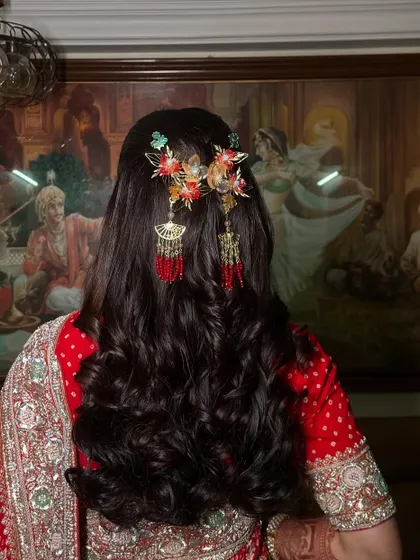 A regal half-updo with soft curls, adorned with beautiful, traditional hair accessories. This hairstyle is perfect for a bride who wants a royal look for her wedding day.