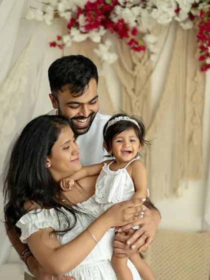 A happy family of three, with the daughter's joyful laugh taking center stage. The floral details in the background add a touch of softness to this lovely portrait.