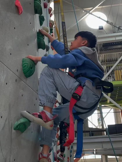 A young climber in his harness makes steady progress up the wall. Our auto belay systems allow kids to climb independently while being completely safe.