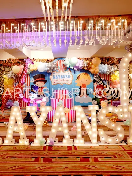A grand stage for a carnival party, featuring large marquee letters, circus animal props, and a backdrop with a ringmaster and zebra.