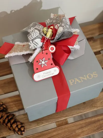 Even a simple gift box is an opportunity for beauty. Here, a Christmas-themed gift is topped with a festive tag and a charming, rustic bow, showing our attention to detail for every occasion.