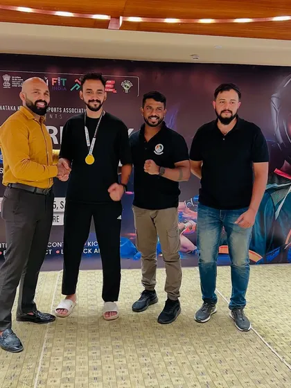 A handshake of respect and victory. A UMC fighter proudly displays his gold medal alongside the coaching staff after a successful competition.