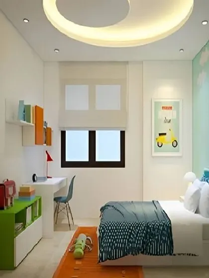 A clean and bright kids' room with a simple circular false ceiling light. The design includes a compact desk and open shelving, making it a great study space.
