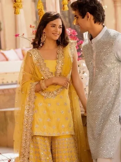 A vibrant and festive look perfect for a Mehendi or Sangeet. The groom's light blue sequined kurta provides a beautiful contrast to the bride's bright yellow sharara set.