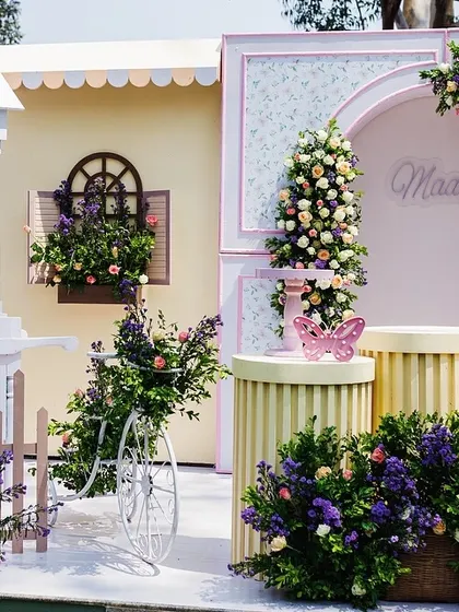 A detailed view of the cake table area, featuring a floral-covered arch, a vintage-style bicycle, and butterfly accents. I combine different props and textures to create a visually rich display.