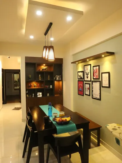 A view of a modern dining area with a dark wood table and bench. The gallery wall and focused lighting create a personal and intimate space for family meals.