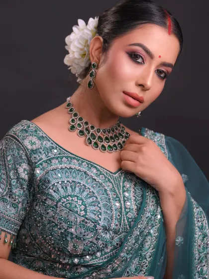 This Bengali-inspired bridal look features a prominent red bindi and beautifully defined eyes. The hair is styled in a traditional bun adorned with fresh flowers, a technique we cover in detail.