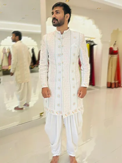 This timeless white Chikankari sherwani is paired with classic dhoti pants. It's a perfect blend of traditional craftsmanship and modern tailoring for the sophisticated Indian man.