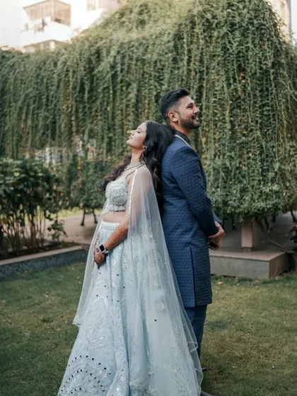 A creative back-to-back pose in a beautiful garden setting. This engagement portrait is both stylish and symbolic of their supportive partnership.