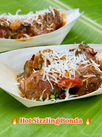 Another look at the Hot Sizzling Bonda, topped with grated cheese that melts into the spicy sauce. This dish is the perfect combination of heat, flavor, and texture.