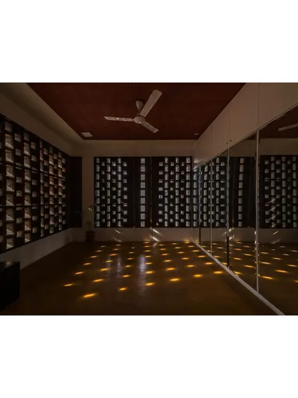 A dance room where the walls are made of perforated brick jaalis. As the sun moves, a grid of light spots travels across the floor, creating a magical and inspiring atmosphere for movement.