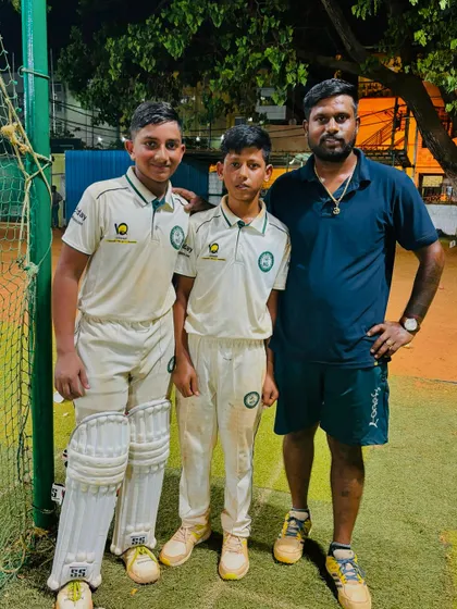 A coach with two of his students at the nets after a practice session, providing feedback and encouragement.