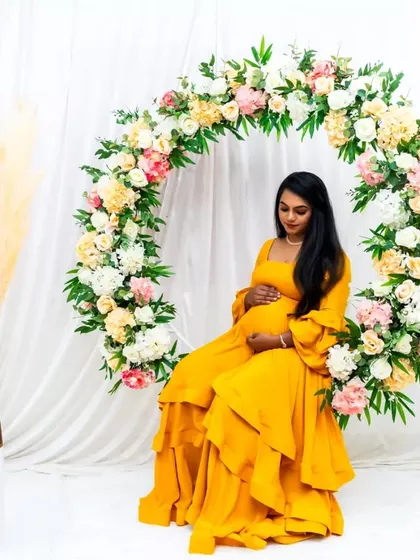 Our yellow maternity gown looks stunning against a floral backdrop, creating a perfect setting for your photoshoot.