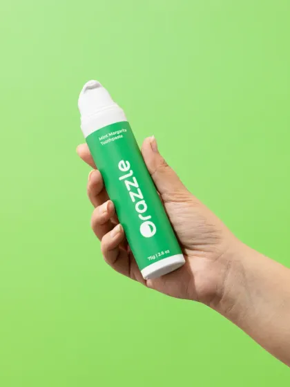 A simple hand-held shot of Orazzle toothpaste. This type of image is great for showing the product's scale and creating a personal, user-focused connection.