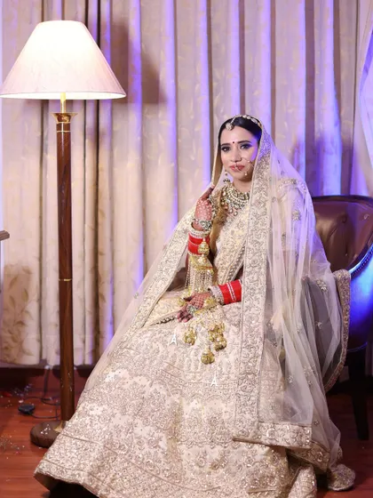 A regal bridal portrait. The bride is seated, allowing her magnificent lehenga to be fully displayed, creating an image of grace and elegance.