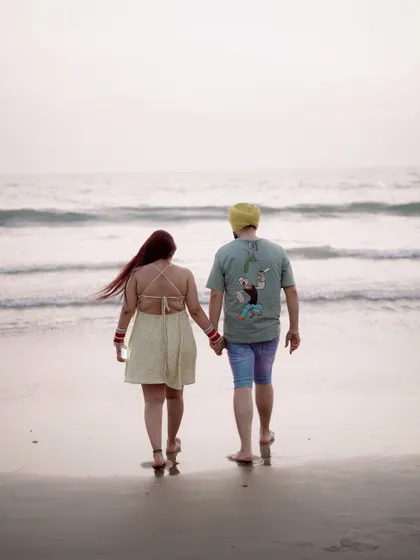 Walking hand-in-hand along the shoreline. This is a classic and beautiful shot that captures the romance and tranquility of a beach photoshoot.