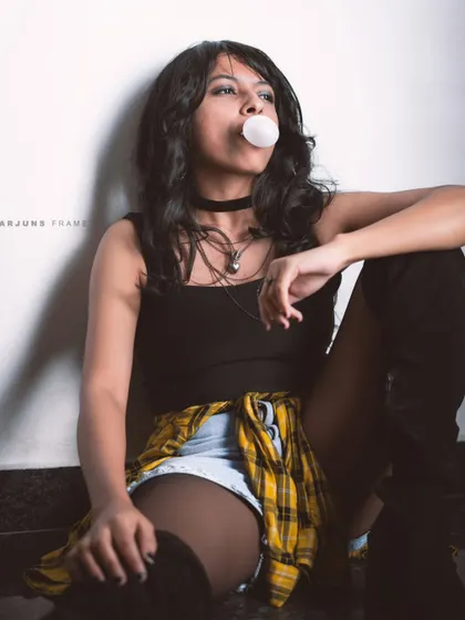 Capturing a classic rebellious vibe with bubblegum and a casual pose. This look, with a flannel shirt and denim shorts, is a nod to 90s urban decay and street style.