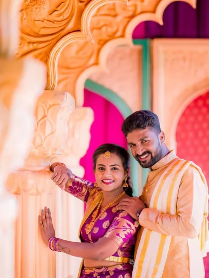A happy, candid moment captured between pillars. The couple's bright, traditional outfits and their genuine smiles make this a very lively portrait.