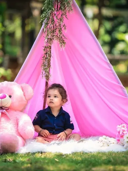 A peaceful moment during an outdoor teepee photoshoot. The little girl sits quietly with her giant pink teddy bear, creating a sweet and serene portrait.