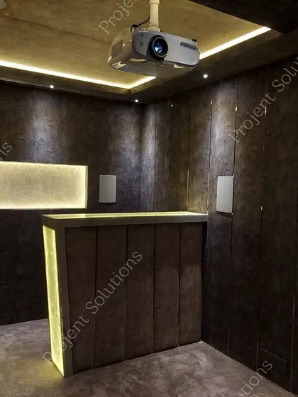 A look at the technical heart of a home theater, featuring a ceiling-mounted 4K projector, precisely placed wall speakers for surround sound, and a custom-built bar area for entertaining guests.