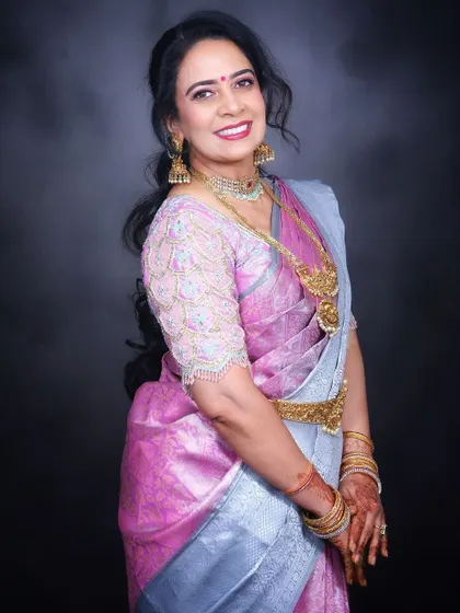 A beautiful portrait of a client ready for a wedding. Her look features soft, glowing makeup and a gracefully draped pink and silver Kanjivaram saree.