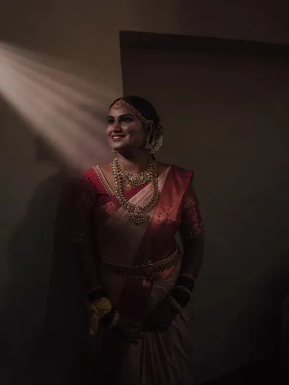 A beautifully lit, moody portrait of the bride in her traditional wedding saree.