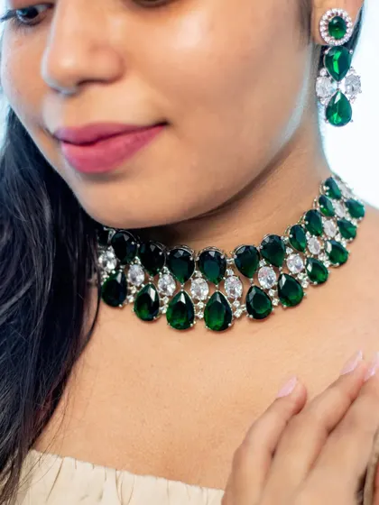 A close-up of a bold and beautiful emerald and zircon choker. This piece is designed to be the star of the show, perfect for pairing with a simple gown or a chic cocktail dress.