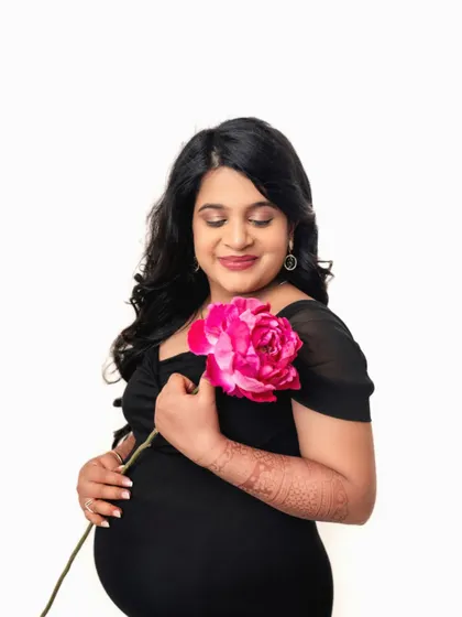Adding a single pink flower as a prop brings a pop of color and softness to this elegant portrait against a white backdrop.