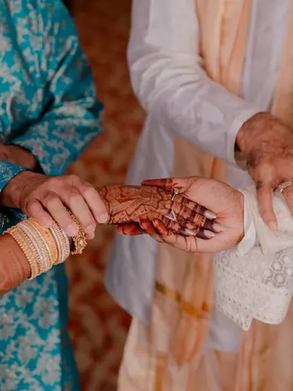 A close-up on the hands during a wedding ritual, symbolizing the union of the couple and their families.