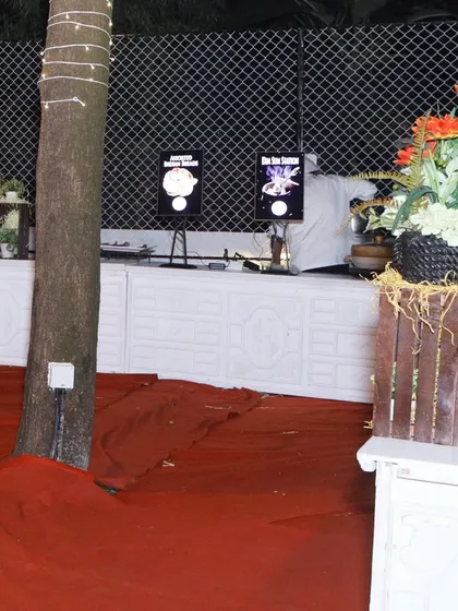 A view of our food stations integrated into an outdoor setting. We use decorative elements like plants and wooden crates to ensure the catering setup blends seamlessly with the event's overall decor.