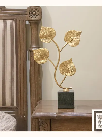 This 'Bloom Leaf' decor features four golden leaves on a delicate branch, set on a dark marble base. It's a simple yet elegant piece of tabletop art that brings a touch of nature indoors.