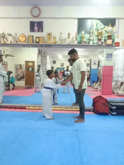 A young student receives his blue belt with a respectful handshake.