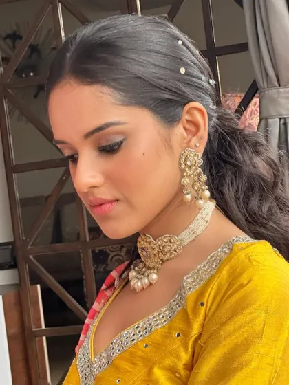 A fresh and modern Haldi look. I created a clean makeup look with a pop of pink on the lips and styled her hair in a chic, pearl-studded ponytail.