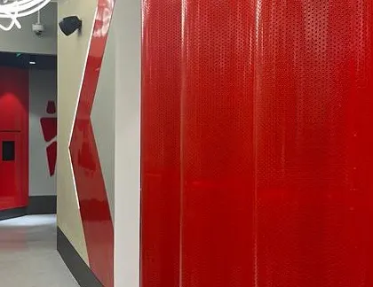 The corridor leading to the wet areas, featuring bold red perforated metal walls and stylized signage. The design ensures that even transitional spaces are impactful and aligned with the gym's high-energy brand.