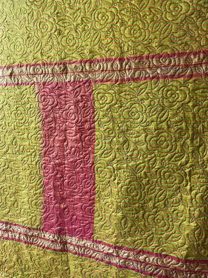 Detail of a lime green and pink saree quilt. You can see how the original zari border is carefully stitched into the new design.