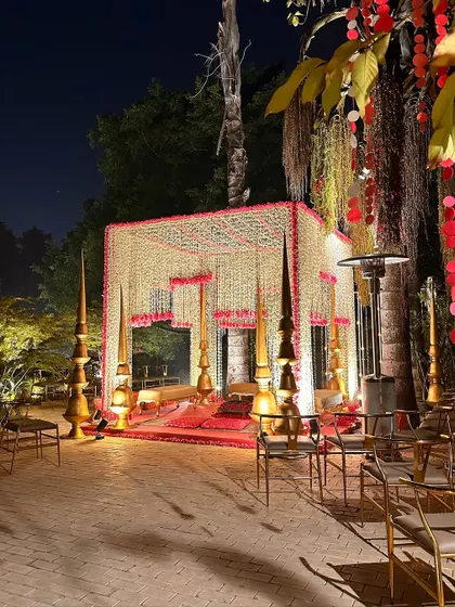 A stunning mandap made of white and red floral strings, set up for a night ceremony. The golden spires add a touch of royalty.