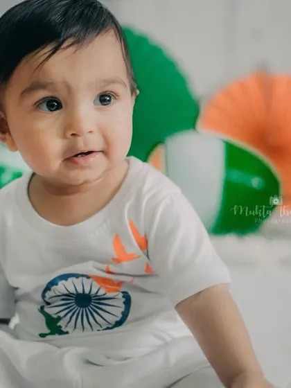 A close-up shot that highlights the baby's expressive eyes and the details on his patriotic-themed t-shirt.