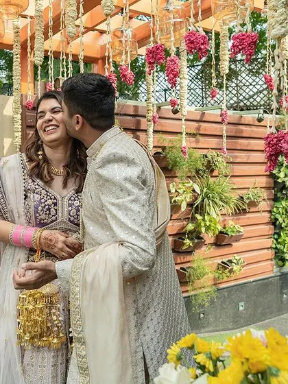 A candid moment of affection between the couple, surrounded by flowers and their loved ones.