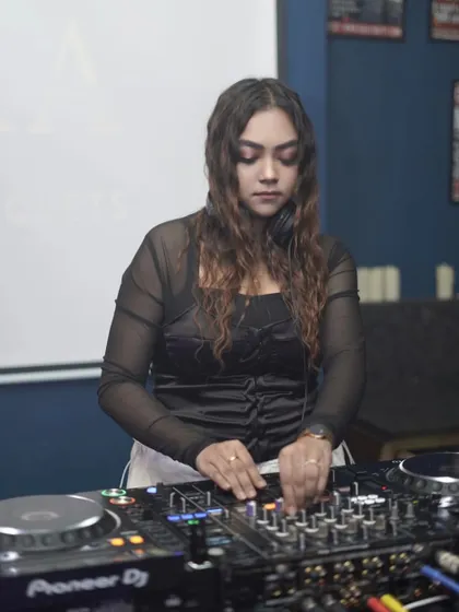 Head down, headphones on. A classic DJ pose showing deep concentration on the music.