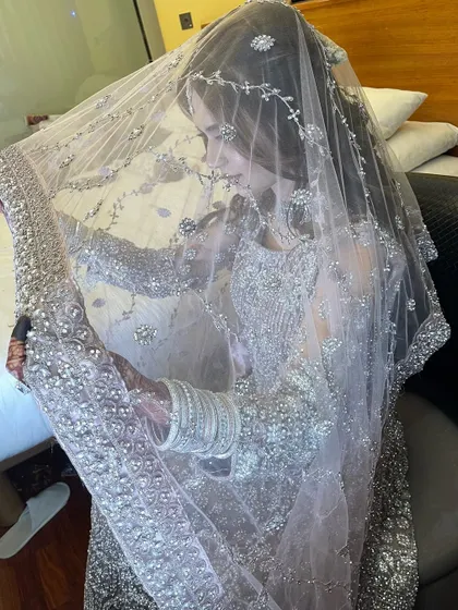 A beautiful, candid shot of the bride under her delicate, embellished veil. This captures a quiet, intimate moment before her reception.