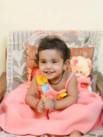 A sweet, smiling portrait of the birthday girl in her pretty pink dress, just before the cake smash fun begins.