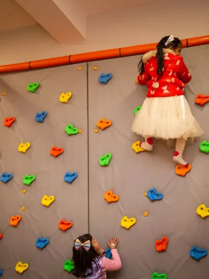 On the way to the top! Our padded rock climbing wall offers a safe challenge for little climbers, with holds of all shapes and colors.